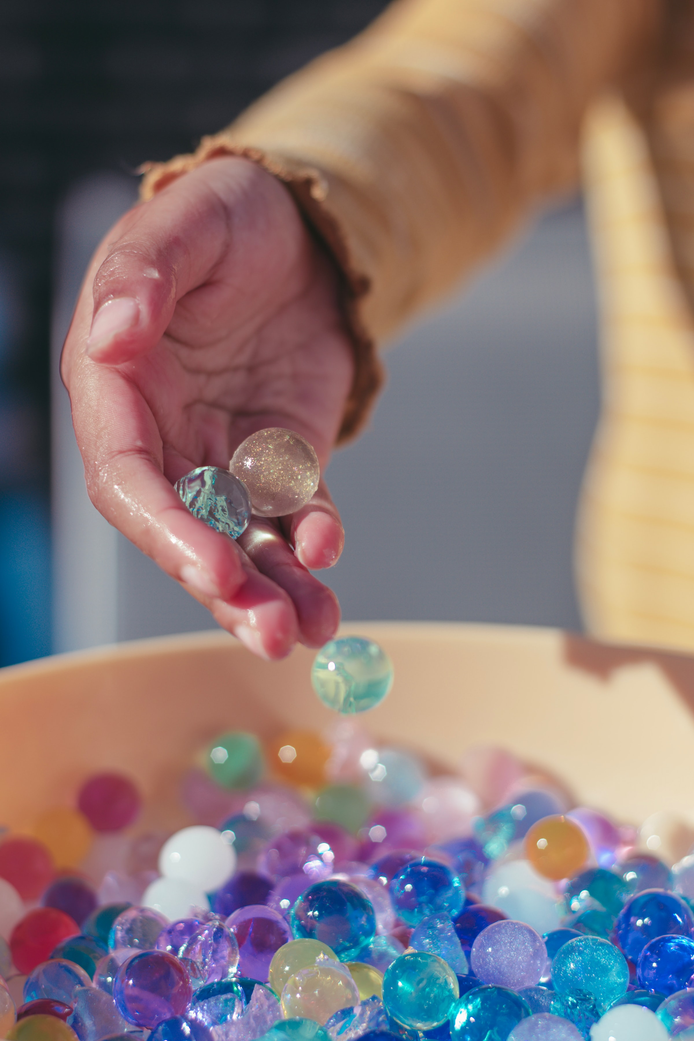 a child's hand scooping up sensory water beads