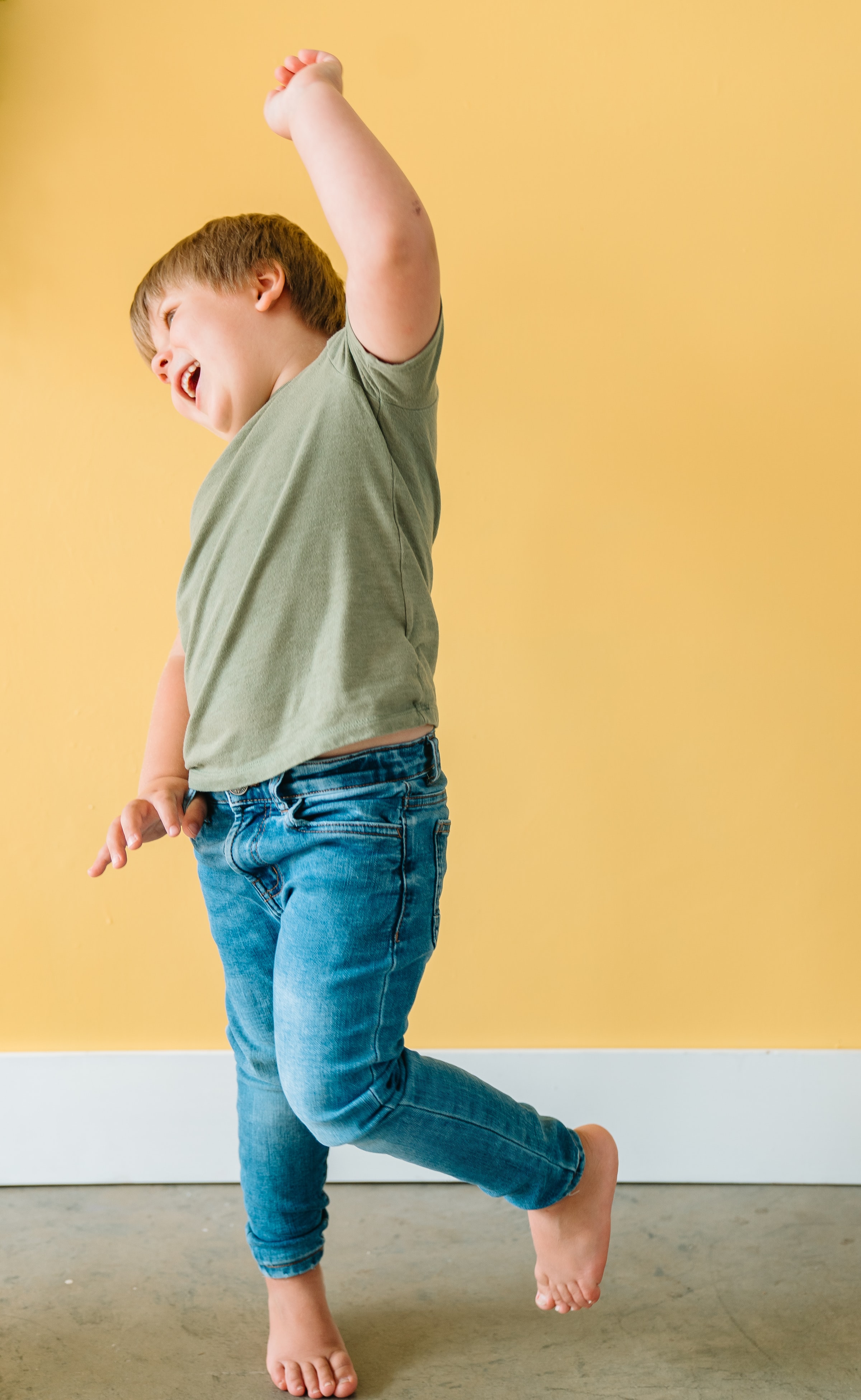 a boy dancing in front of a yellow wall