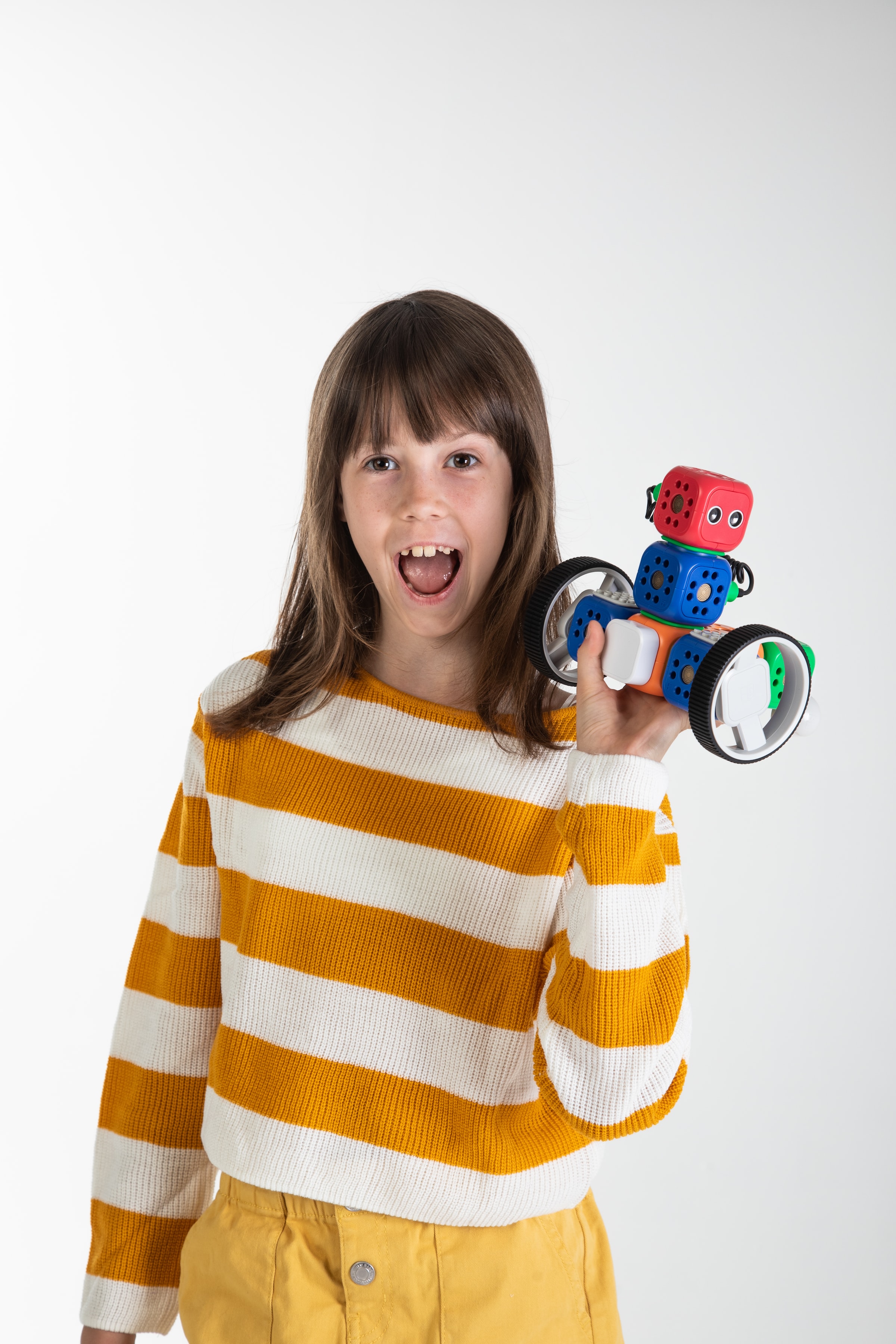 a smiling child holding a small robot in one hand