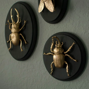 image of golden bugs on a black wooden plaque
