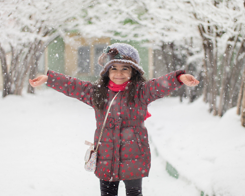Image of a smiling child standing in a snowy field