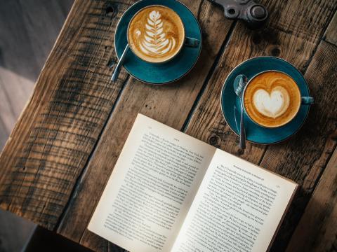 a book lying open beside two cups of coffee